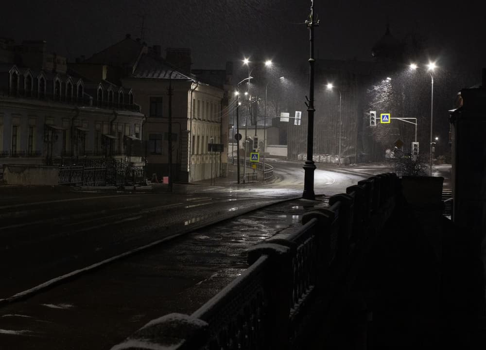 A city street at night in the rain, empty under the streetlights