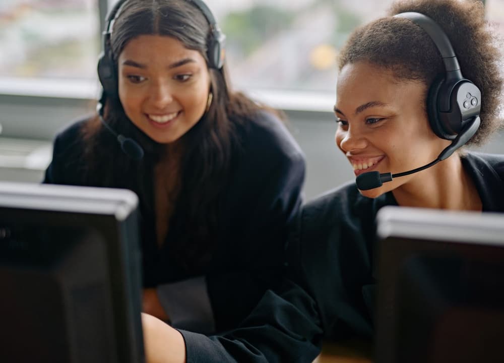 Two people in headsets working one monitor between them