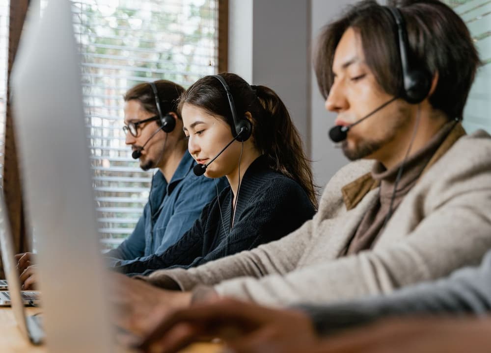 Three call-centre agents in headsets on a shared floor