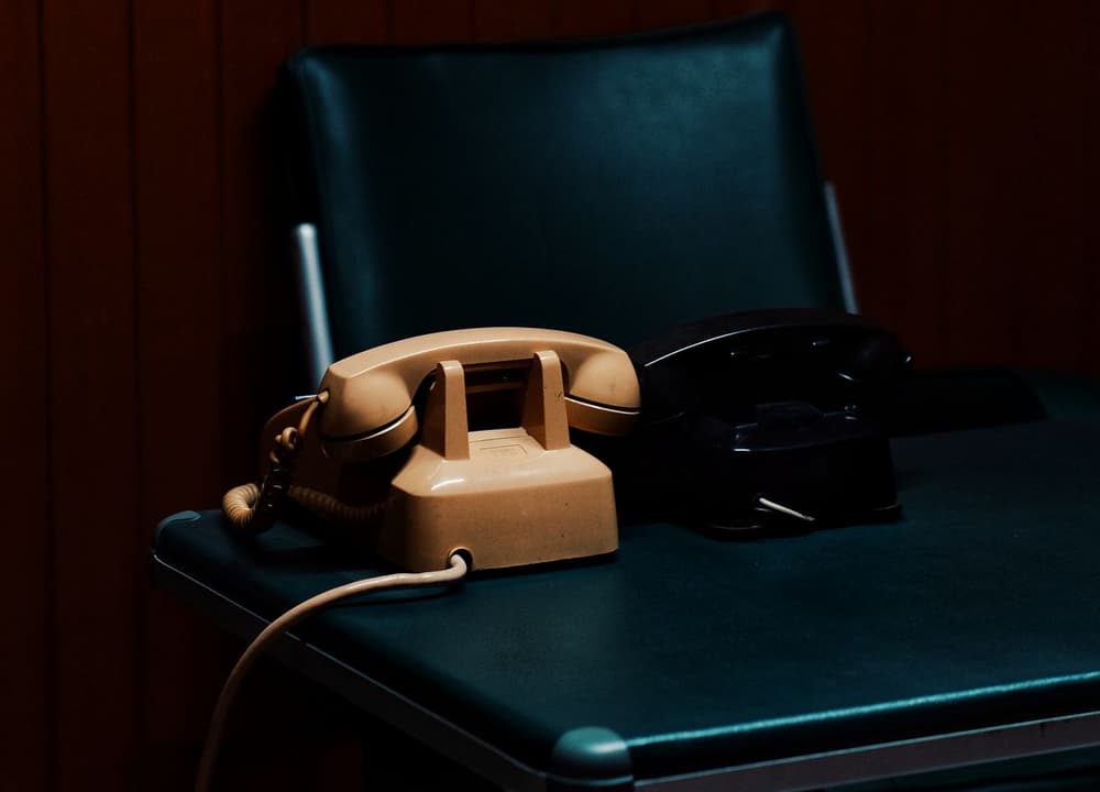 A desk phone beside an open laptop in a small office