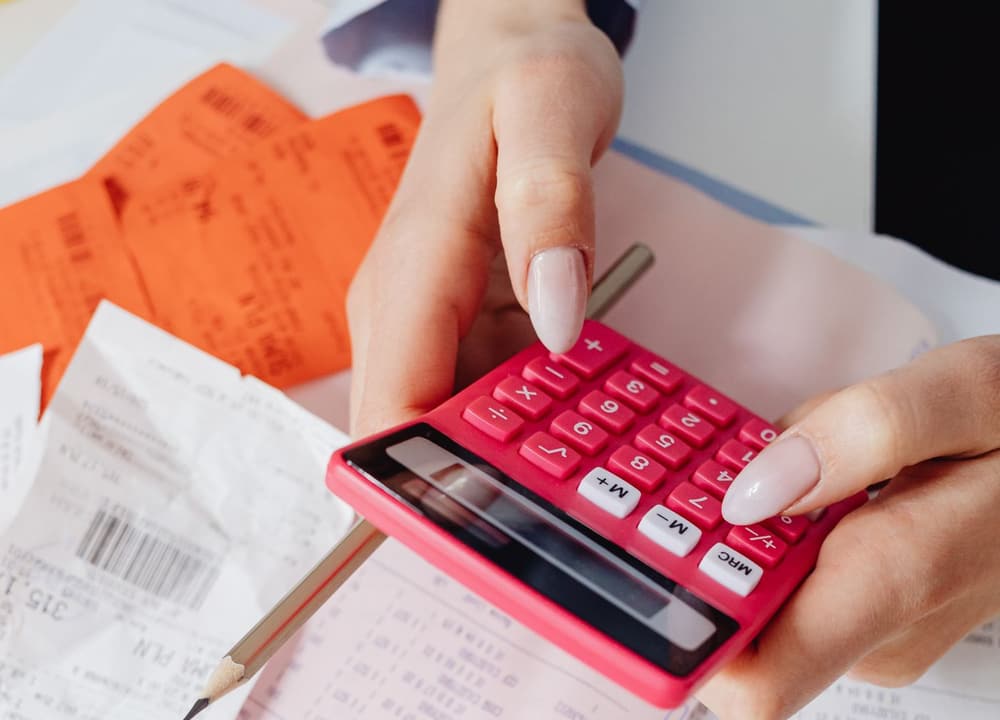 Hands working a calculator among receipts and invoices