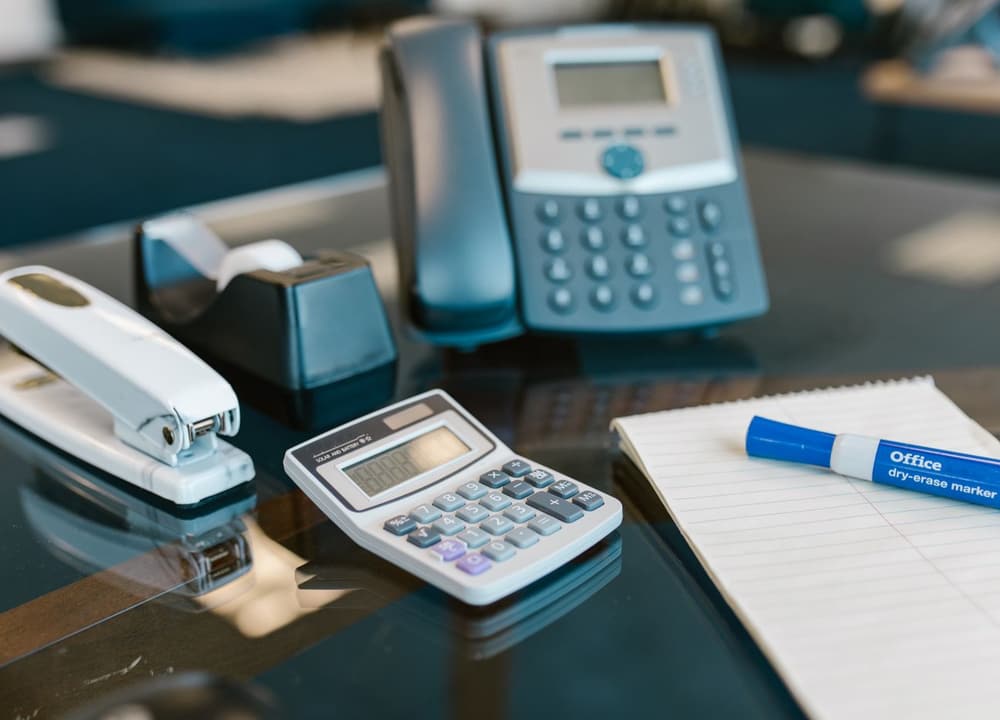 A desk with a telephone and a calculator side by side